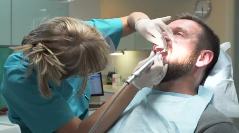 Dentist polishing teeth of young client. Steadicam. Vídeo Stock 68522434