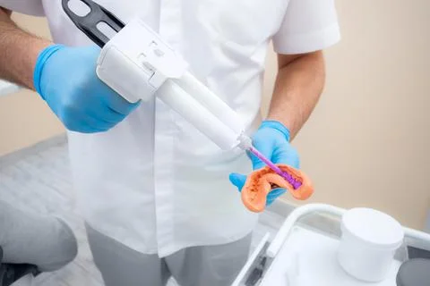 Dentist prepares material for a mold of teeth. Close-up of a dentist in blue Stock Photos