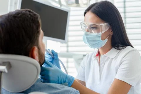 Dentist at procedure using dental drill for client in modern dental clinic Stock Photos