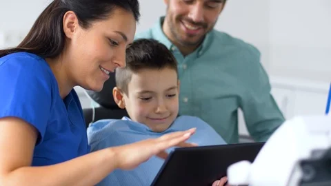 Dentist showing tablet pc to kid at dental clinic Stock Footage