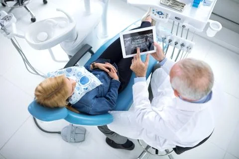 The dentist shows patient whose teeth need to be repaired Stock Photos