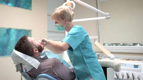 Dentist sits down and examining teeth of patient. Slider shot, right. Vidéo 68524005