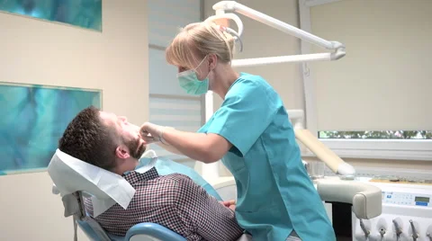 Dentist sits down and examining teeth of patient. Slider shot, left. Vídeo Stock 68524306