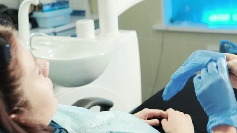 Dentist sits next to client puts on blue protective gloves Stock Footage 71633456