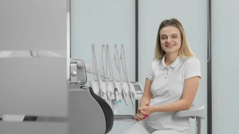 Dentist sitting and looking at camera. The dental clinic operates on modern Stock Footage 250125396