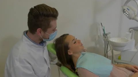 Dentist is Sitting Behind a Client's Head Talking Man in Mask is Examining a Stock Footage 60973801
