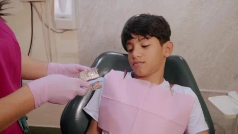Dentist teaching young boy brushing technique Stockbeeldmateriaal 346075512