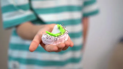 Dentist test setting of palatal braces for young patient in child's hand. Stock Footage 256069414