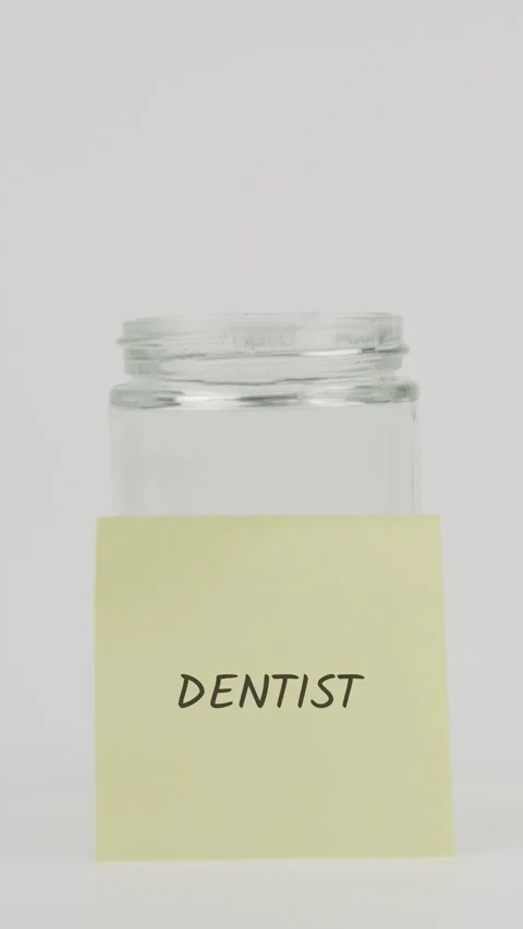 Dentist text or word on yellow sticky note attached to glass jar with hand Stock Footage 311713435