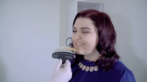 Dentist with tooth color samples choosing teeth color at dental clinic Stock Footage 106094271