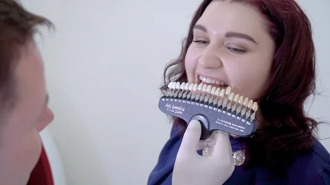 Dentist with tooth color samples choosing teeth color at dental clinic Stock Footage 106204982