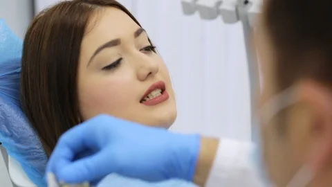 Dentist with tooth color samples is choosing shade for woman patient teeth Stock Footage 108978970