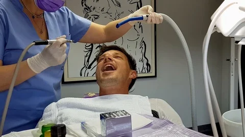 A dentist treating a patient with a dental drill and a suction tool Stock Footage 106988018