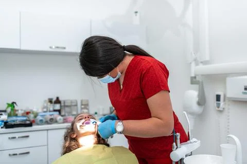 The dentist uses an ultraviolet lamp while fitting the girl with braces Stock-Fotos
