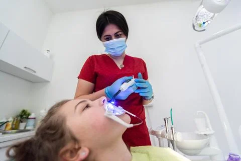 The dentist uses an ultraviolet lamp while fitting the girl with braces Stock Photos