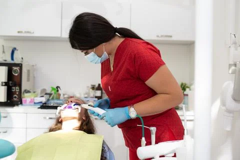 The dentist uses an ultraviolet lamp while fitting the girl with braces Stock-Fotos