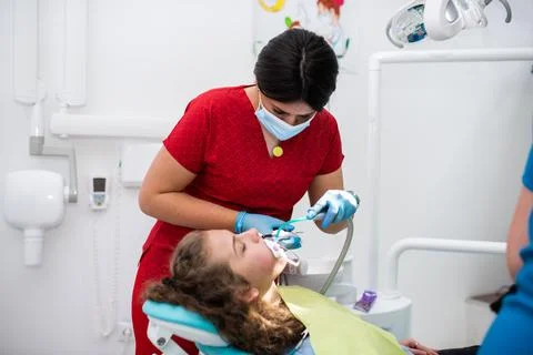 The dentist uses an ultraviolet lamp while fitting the girl with braces Stock-Fotos
