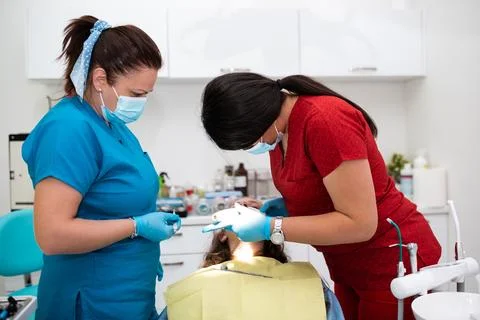 The dentist uses an ultraviolet lamp while fitting the girl with braces Stock Photos