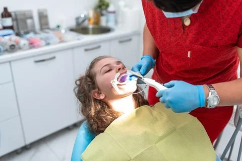 The dentist uses an ultraviolet lamp while fitting the girl with braces Foto stock