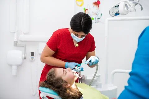 The dentist uses an ultraviolet lamp while fitting the girl with braces Stock Photos
