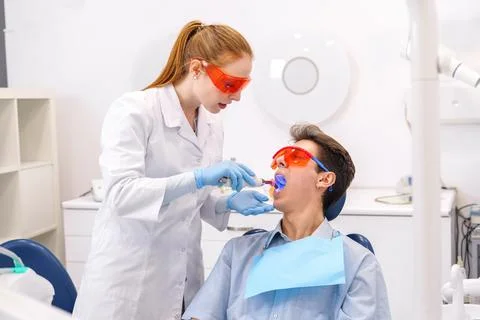 Dentist using curing light on patient Foto stock