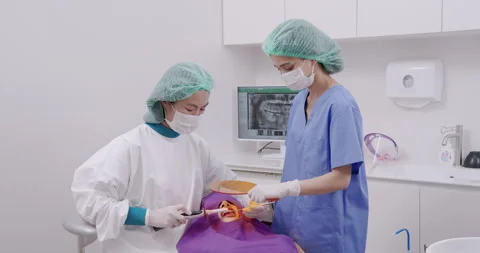 Dentist using curing light tool while performing composite filling on asian Stock Footage 314412555