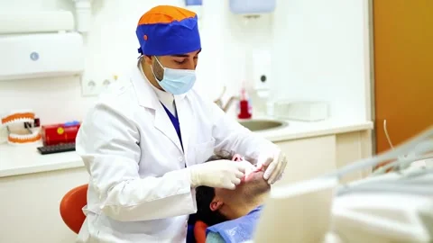 Dentist using dental floss to clean patients teeth Stock Footage 295627188