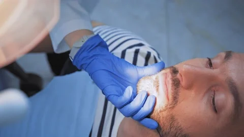 Dentist using dental instrument while working with patient in clinic Stock Footage 136187551