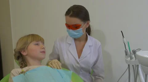 Dentist is Using a Dental Lamp Treating a Teeth Patient Girl Doctor in Glasses Stock Footage 60981503