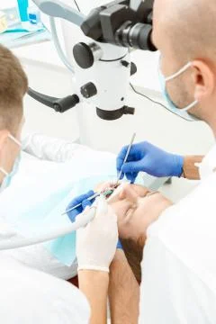 Dentist using dental microscope during inspection Stock Photos