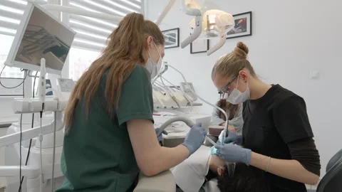 Dentist using drill and suction on teenage boy tooth in dental clinic Stockbeeldmateriaal 330121789