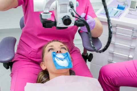 Dentist using microscope  for operation of a woman patient Foto stock