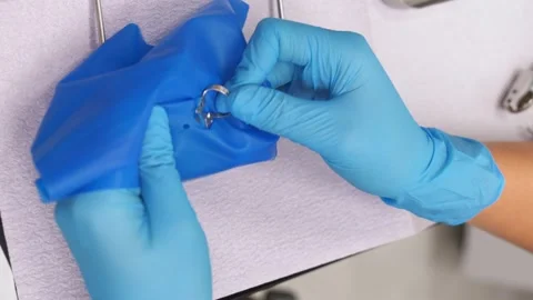 Dentist using rubber dam system with latex scarves, piercing hole Stock Footage 258687946
