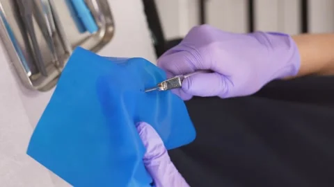 Dentist using rubber dam system with latex scarves, piercing hole Stock Footage 258688410
