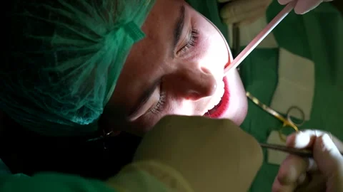 Dentist using stitching thread to sew female patient gums during dental Stock Footage 299980604