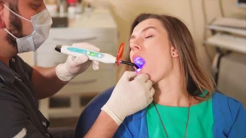 Dentist using ultraviolet lamp on patients teeth. Stock Footage 76875333