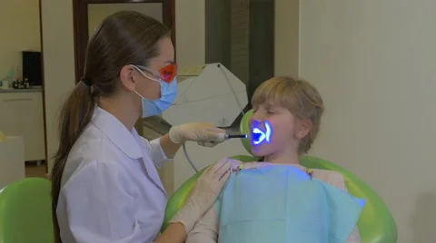 Dentist is Using a uv Lamp Patient is Smiling Doctor in Glasses and Mask is Stock Footage 60980764