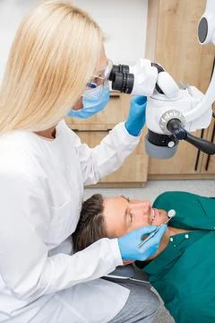 Dentist while working. Treatment teeth to a patient using a microscope at den Fotos de archivo