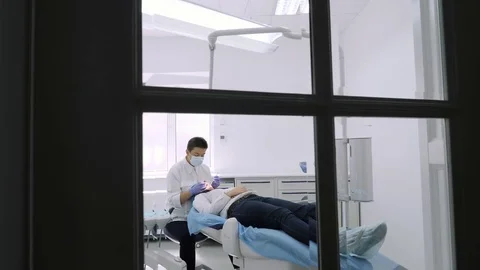 Dentist at work view, camera tracking through a window into the dental office. Stock Footage 81469149