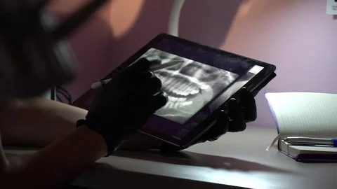 Dentist is working on the tablet in the office with stylus pen. Doctor in Stock Footage