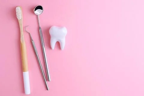 Dentistry concept. Model of a tooth and dental instruments on a colored Stock Photos