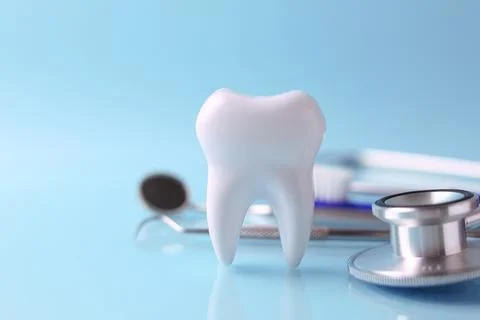 Dentistry concept. Model of a tooth and dental instruments on a colored Stock Photos