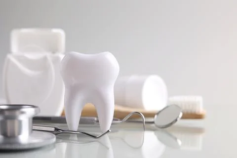Dentistry concept. Model of a tooth and dental instruments on a light background Stock Photos