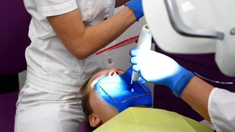 Dentist's assistant fixes a filling in a tooth with a device Stock Footage 197431746