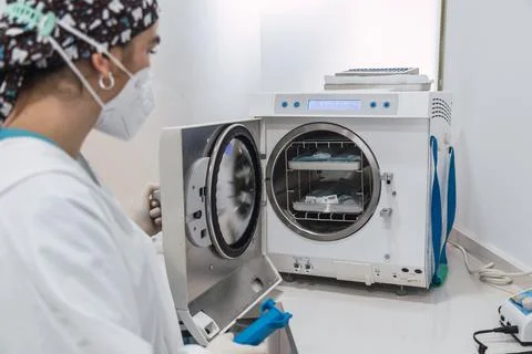 The dentist's assistant insert the packaged dental instrument to the autoclav Stock Photos