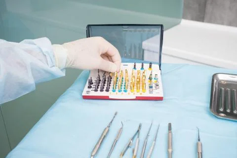 The dentists hand takes the endodontic obstructive dental equipment in the de Stock Photos