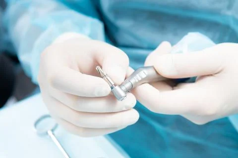 Dentist's hands in sterile gloves close-up, with an implantation tool. Stock Photos