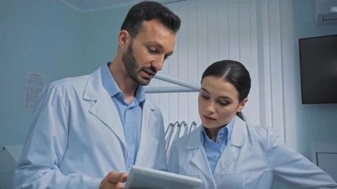 Dentists talking and using digital tablet in clinic Stock Footage 136190116