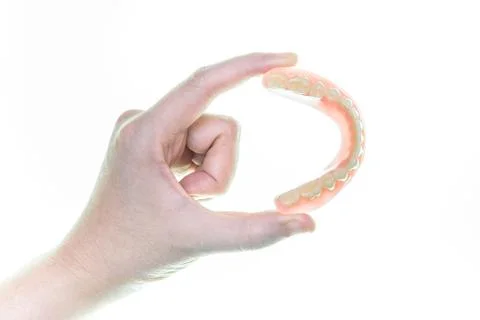 Denture in hand on white background Stock Photos