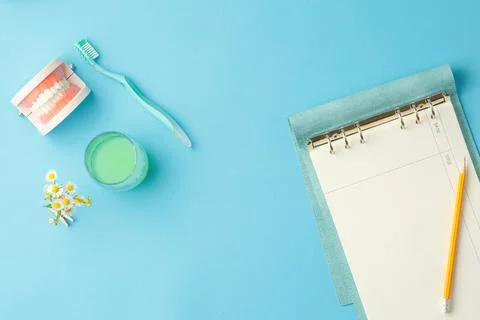 Dentures with toothbrush and notepad on the table. Stock Photos